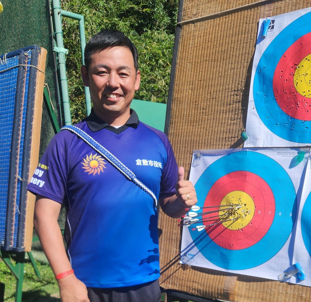アーチェリーの的の横で笑顔を見せる大江佑弥選手